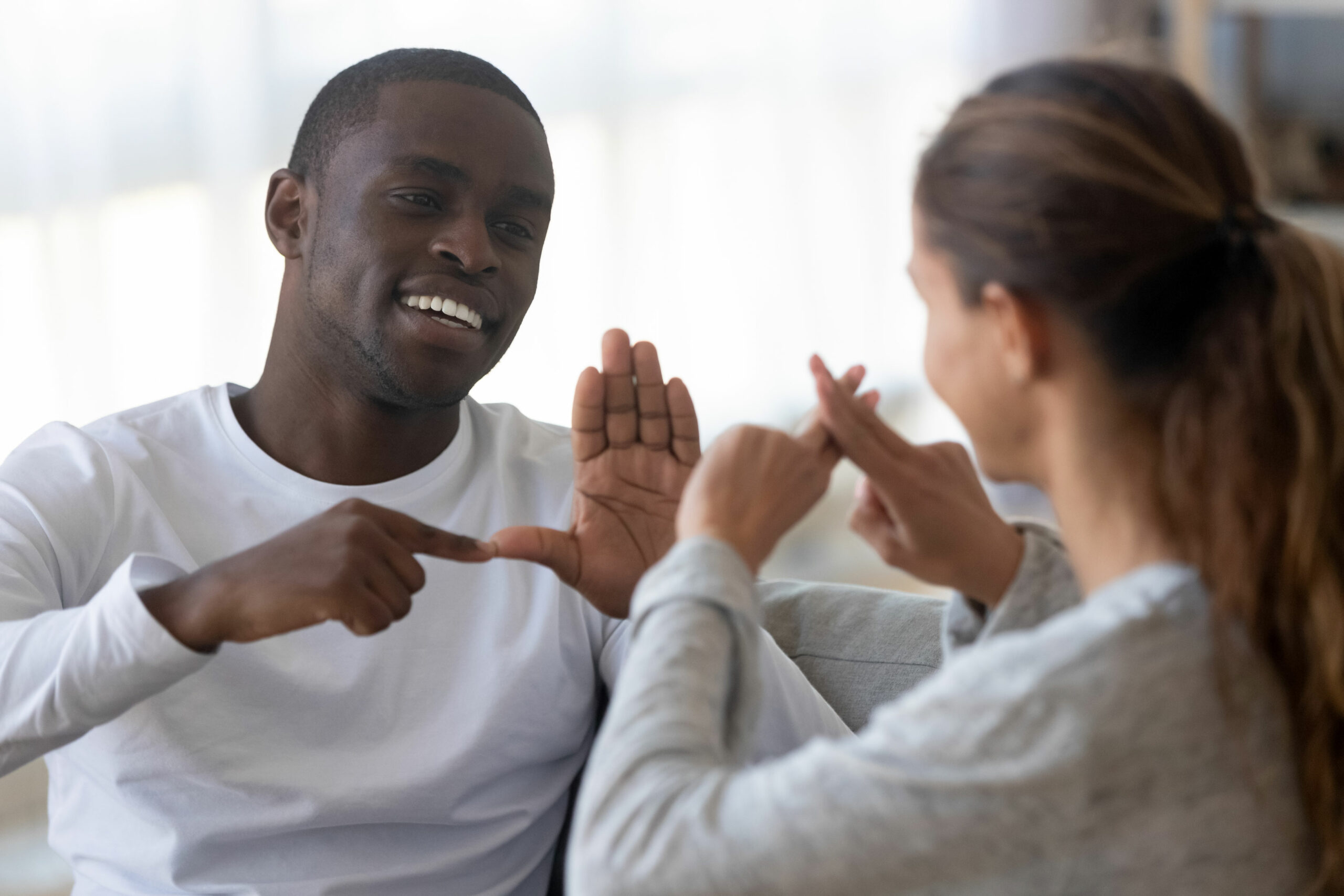 Two people smiling and conversing using sign language